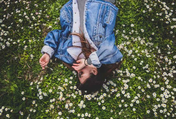 Image of woman laying in daisy field. Whetagrass' green tint comes from chlorophyll that's also found in grasses surrounding this daisy field via Organic Authority.