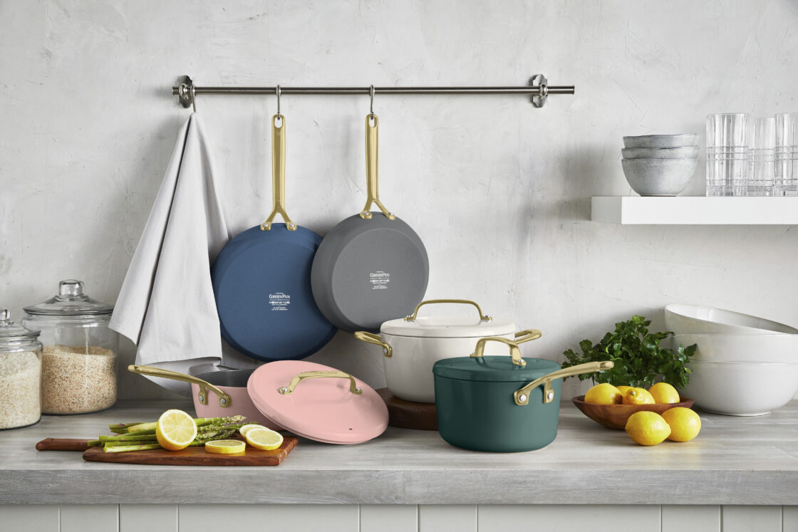 Image of GreenPan GP5 15-piece set in multiple colors for a greenpan review. The set sits on a modern counter with a marble backsplash with a rail used to hang two of the GreenPan non-toxic pans.