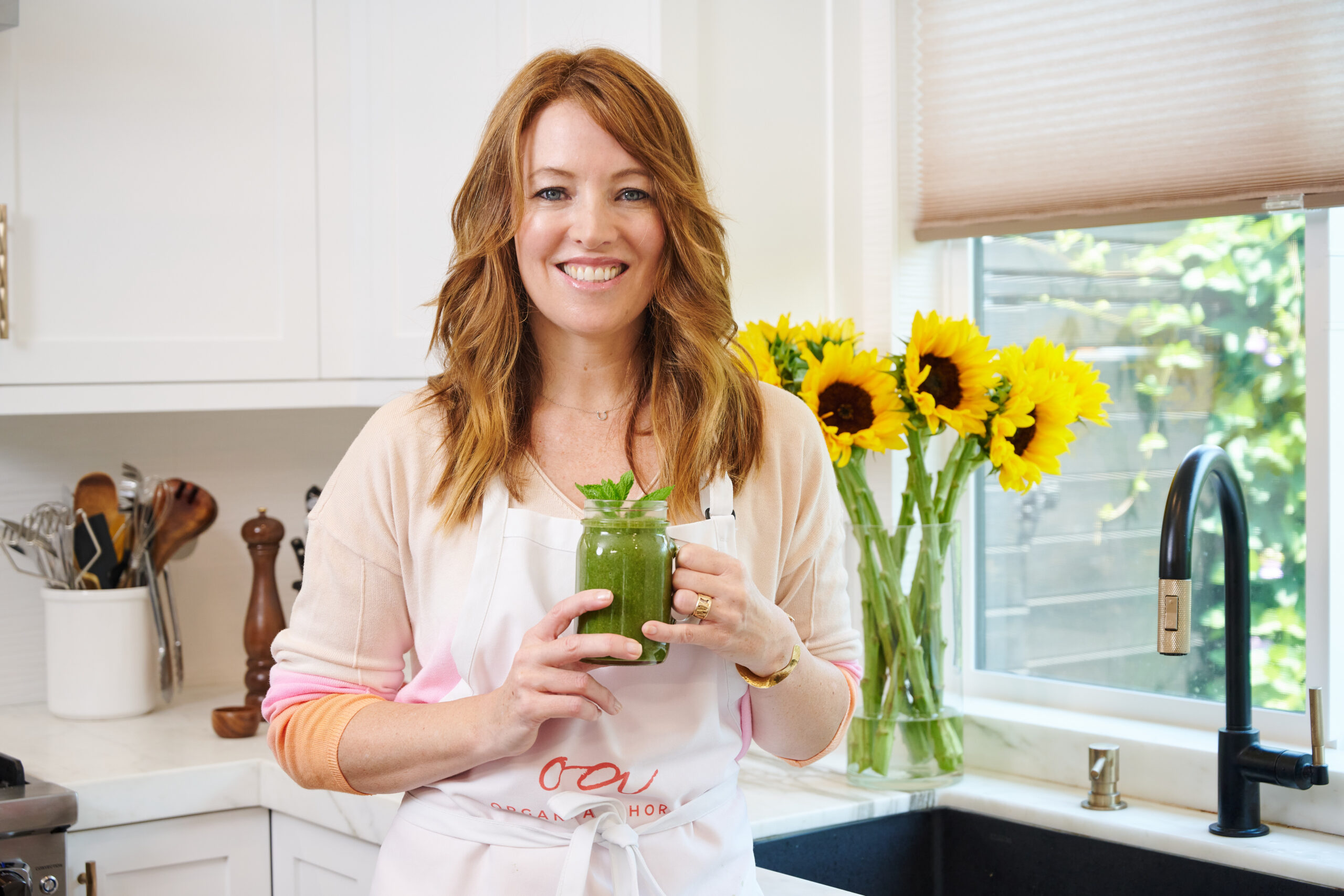 Image of Laura Klein with a healthy chocolate milkshake with mint and spinach in a kitchen with sunflowers and a window. For creamy chocolate milkshakes.