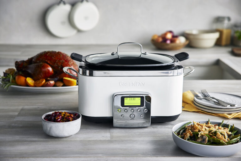 Image of GreenPan's white elite slow cooker on a countertop amongst a finished cooked meal including turkey and green beans.
