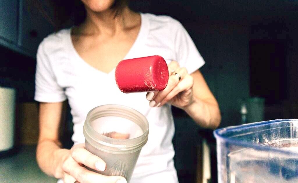 woman pouring powder into drink bottle