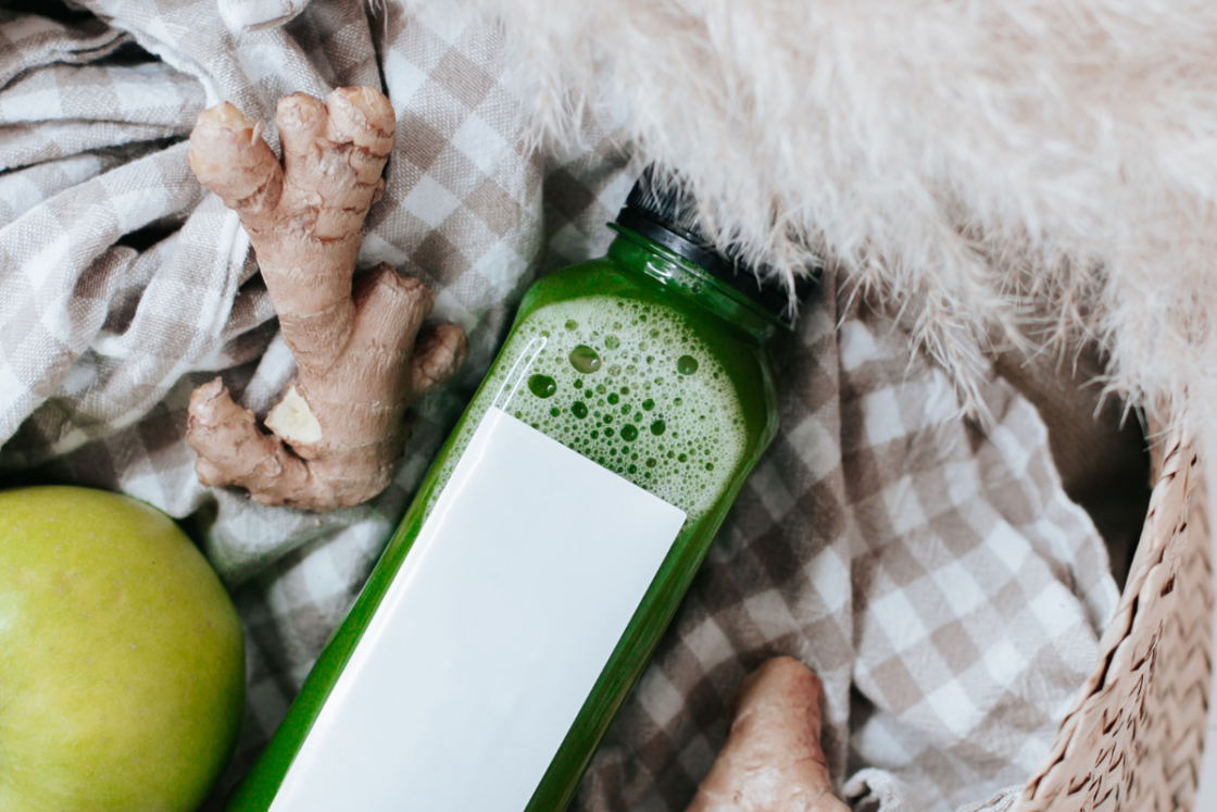 Image of basket filled with a check towel with ginger, apple, and bottle of chlorophyll water on top via Organic Authority. Chlorophyll water is thought to be an easier way to get your this amazing food into your routine. But is it really?