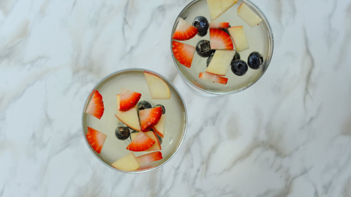 image of a sangria spritzer in cute glasses with floating fruit, strawberries, blueberries and apples.