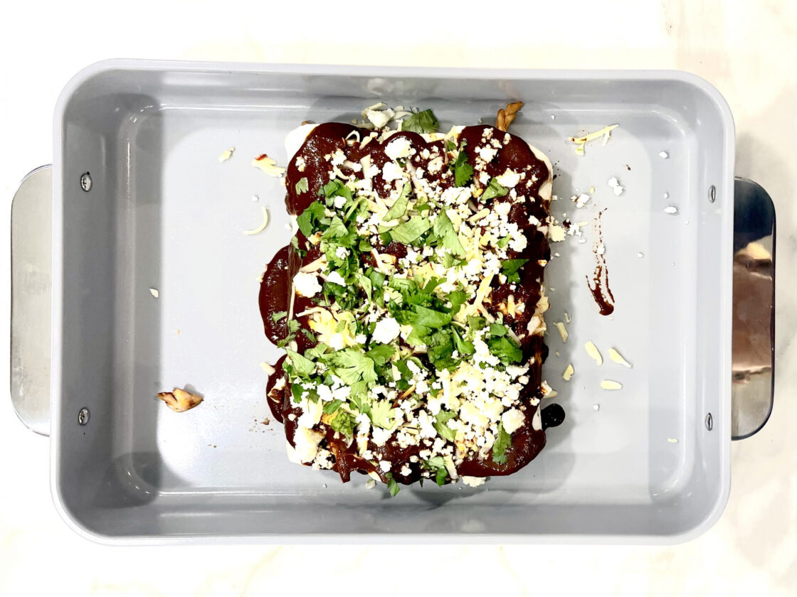 image of Caraway baking pan with enchiladas showing off the nonstick, nontoxic surface with plain white background.