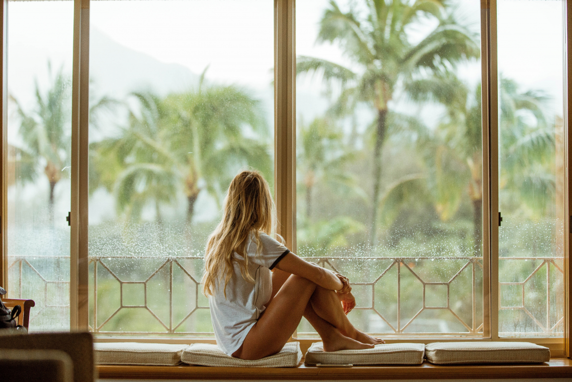 woman sitting at the window looking out at palm trees