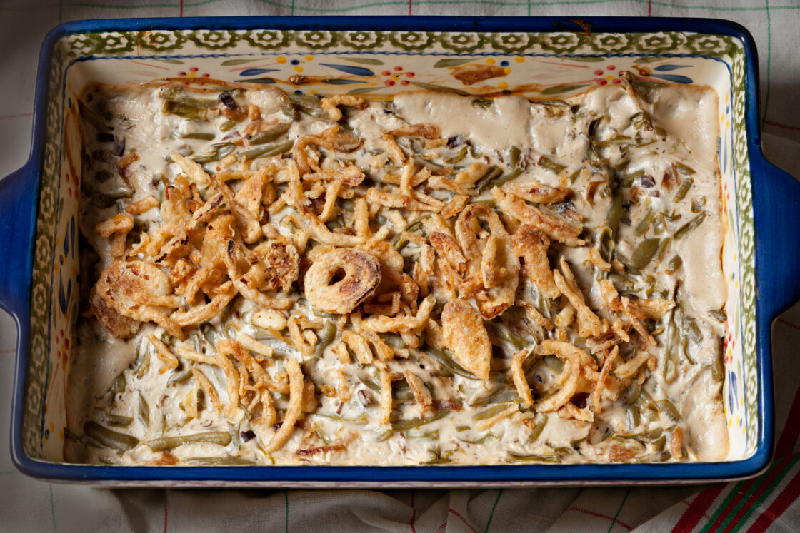 Image of green bean casserole in a baking dish, smothered in creamy sauce.