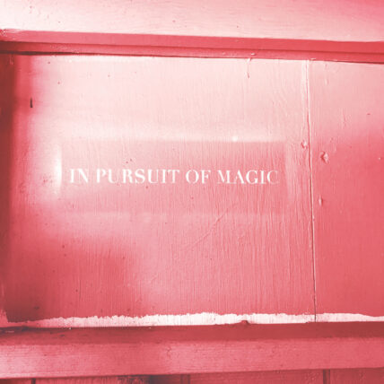 A pink wall with the words "in pursuit of magic" painted in white