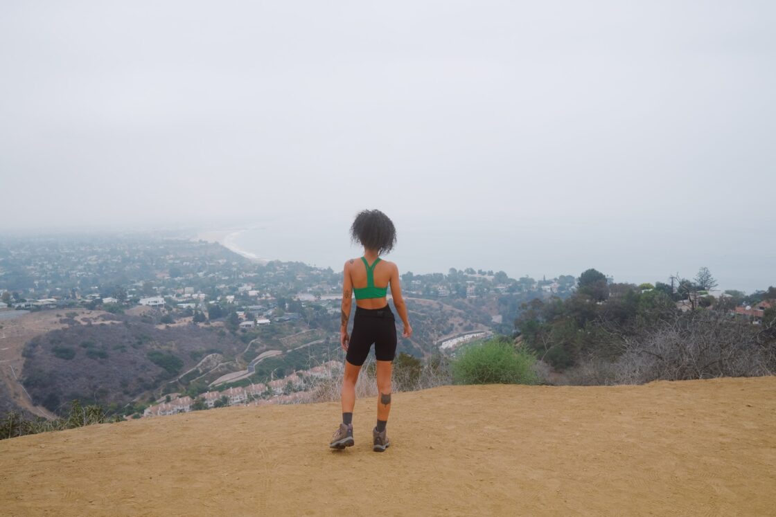 Image of woman on a hike looks out at ocean. Apple cider vinegar may impact hunger by reducing the mealtime glycemic load.