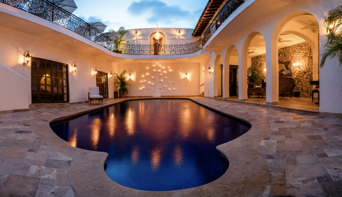 a pool reflecting warm yellow lights in a courtyard at Casa Kimberly in Puerto Vallarta