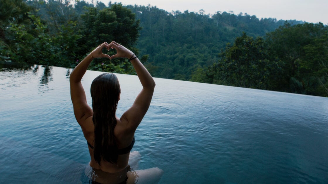 5 ways to biohack your health for improved overall wellness. Woman in pool overlooking forest.