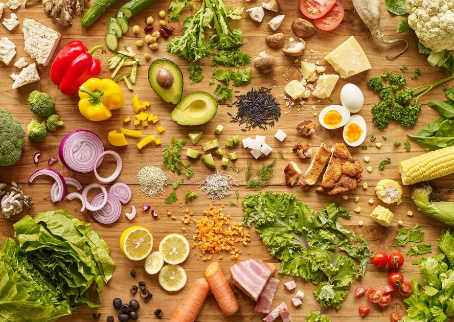 Image of a table covered with a colorful and nutrient-dense assortment of fruits, vegetables, cheeses, and meats that can improve mitochondrial function. 