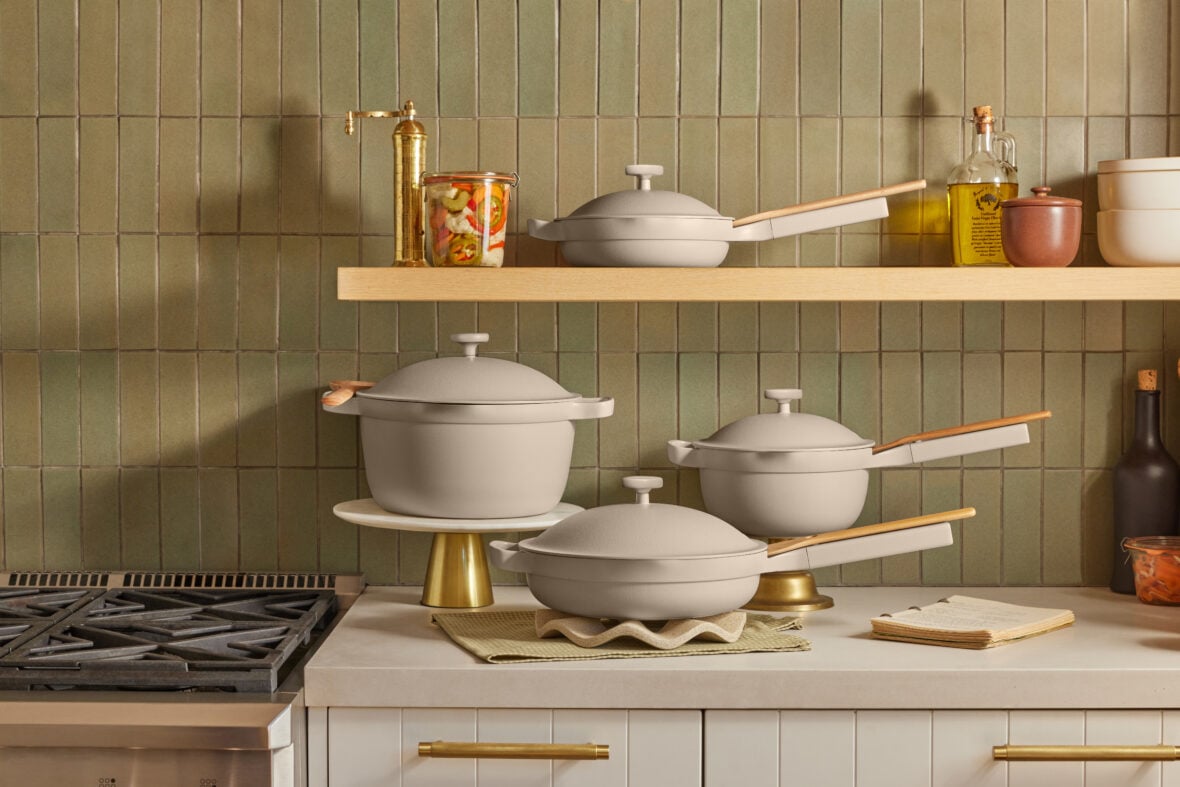 Image of the Always Pan set by Our Place, displayed neatly on a counter next to a stove and shelf