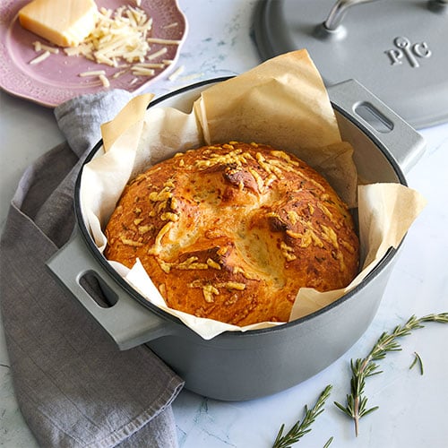 Image of a dutch oven with a whole loaf of bread, which is a great baking gift.