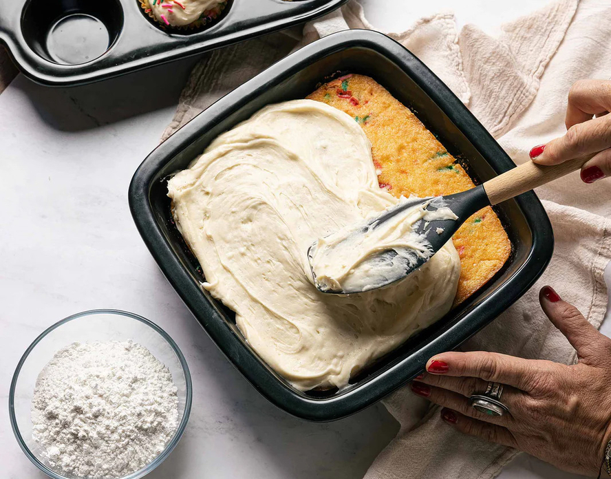 Image of a funfetti cake being frosted in an Xtrema Cookware square cake pan.