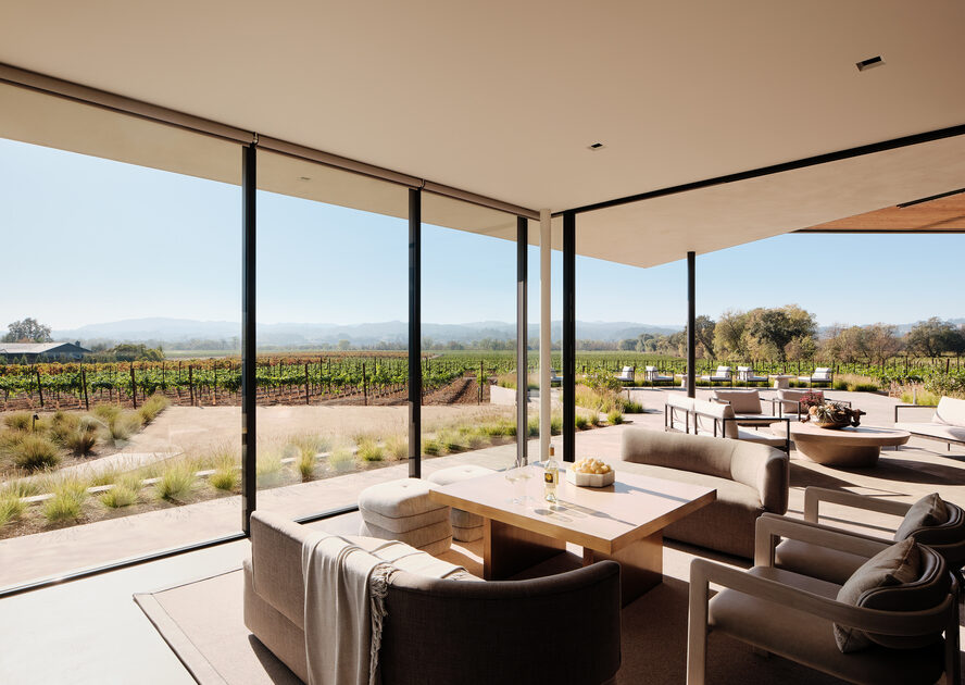 Image of the wine tasting room in Aperture Cellars, with a table and plush seating overlooking an expansive view of the vineyard.