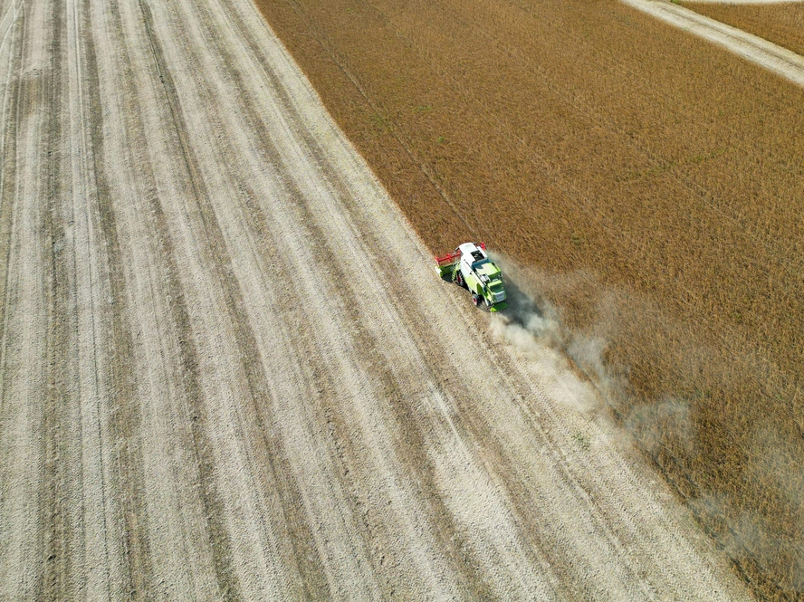 Image of a bird's eye view of agricultural machinery harvesting cropland.