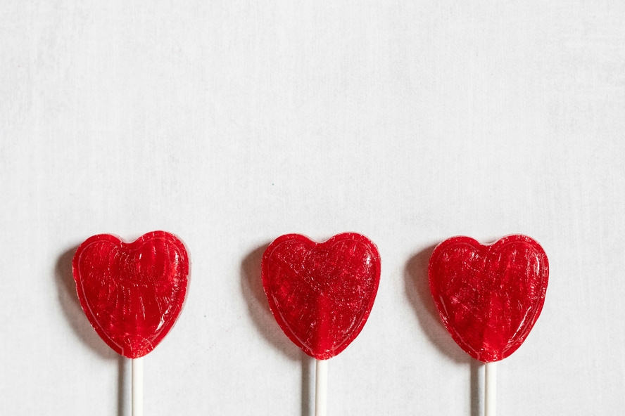 Image of three heart-shaped lollipops, which get their vibrant red color from carcinogenic red 3 dye.