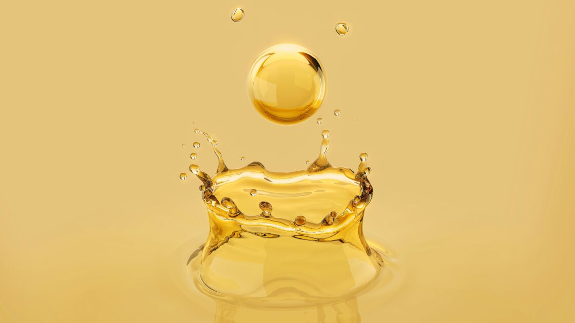 Image of a golden drop of a seed oil dripping and bouncing back into the air.