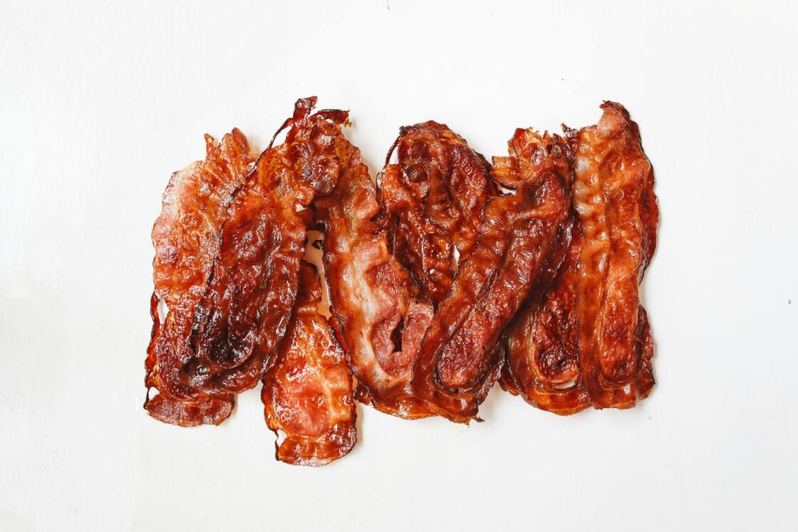 Image of a handful of pieces of crispy fried bacon on a white background.