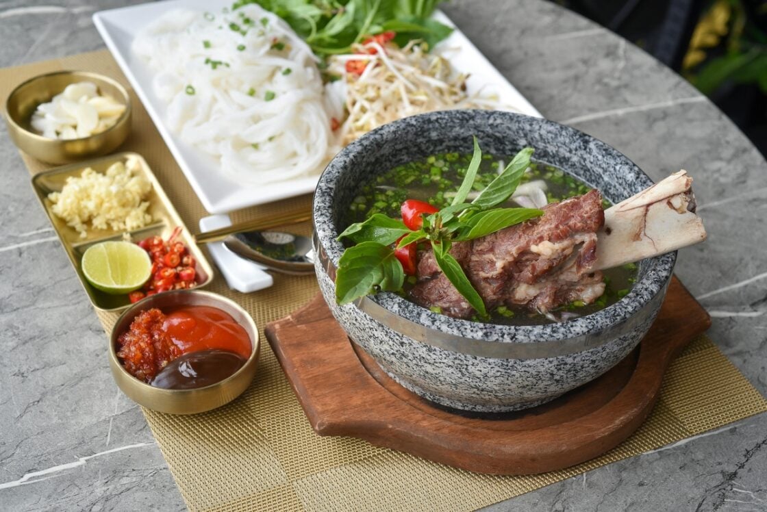 Image of a table covered with various dishes of food — a large bowl with a meat stew can increase how much collagen per day you intake.