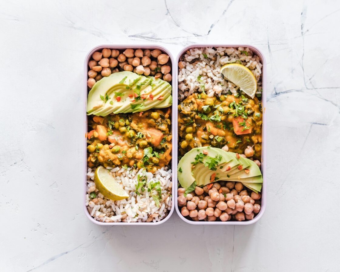 Image of two small lunchboxes filled with rice, avocado, chickpeas and curry.