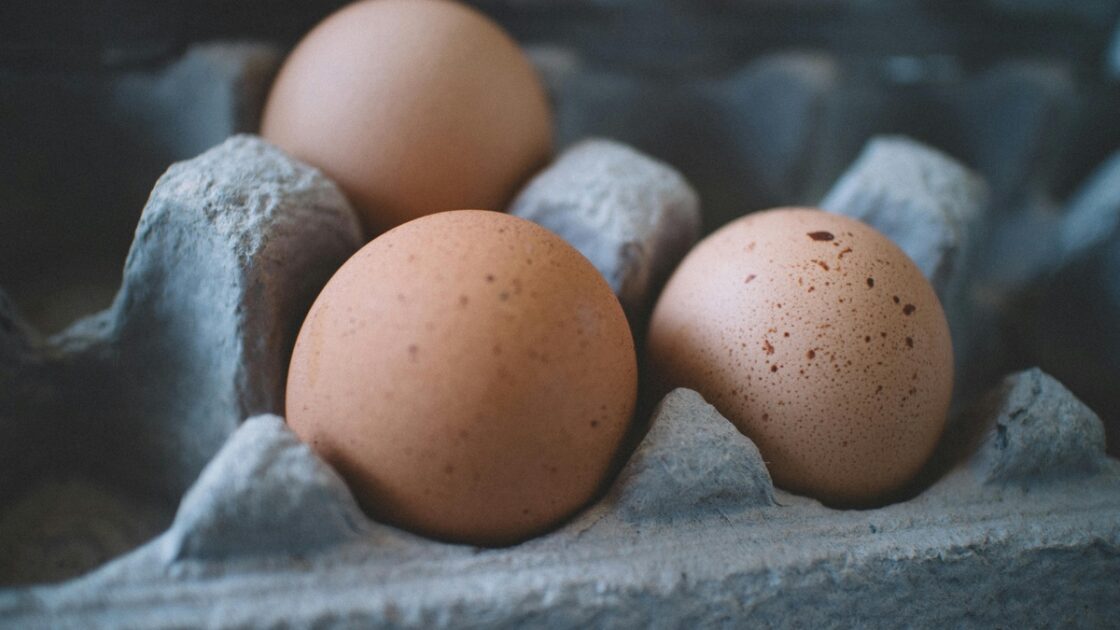 Close-up image of three brown eggs shown in an egg carton.