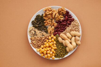 Image of an assortment of nuts, seeds, and beans on a white plate against a brown background.